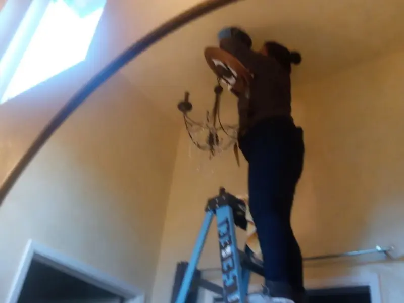 Electrician installing a chandelier in a Bridgeton residence